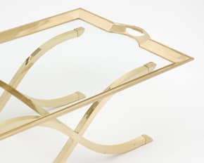 French brass coffee table by French design house Maison Charles. The table features an X shaped base and a detachable tray.