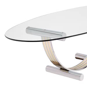 Italian vintage table by Italian designer Romeo Rega. A thick oval shaped glass sits on a harp shaped base made of chrome and brass