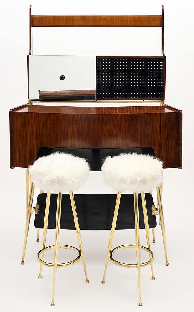 Bar, Italian, made of mahogany and brass. The ensemble features a case on brass legs with a glass shelf and a sliding mirrored door on top, a bar on brass legs of rosewood, and two brass stools upholstered in ivory toned shag fabric. The measurements listed are for the case piece, measurements for each piece are located separately below. 