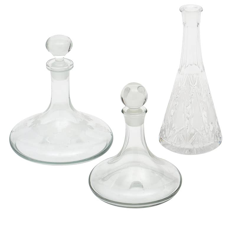 Beautiful set of three vintage French glass decanters. The decanter on the left has an etched pattern of vines and leaves. The center decanter has very beautiful clear glass. The right decanter has cut glass patterns throughout. Measurements listed are for the etched glass decanter. Each decanter can be sold as a single item. The cut glass decanter is priced at $550. The etched glass decanter is priced at $450, and the small glass decanter is priced at $350.
